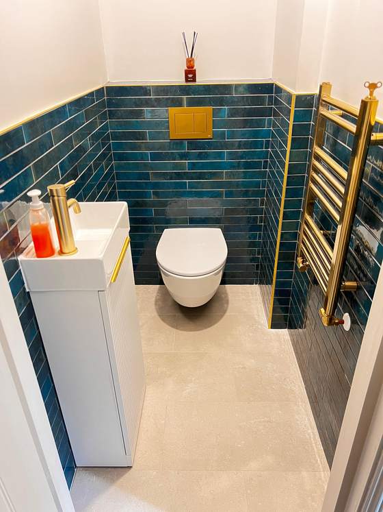 Teal-tiled cloakroom with gold fittings