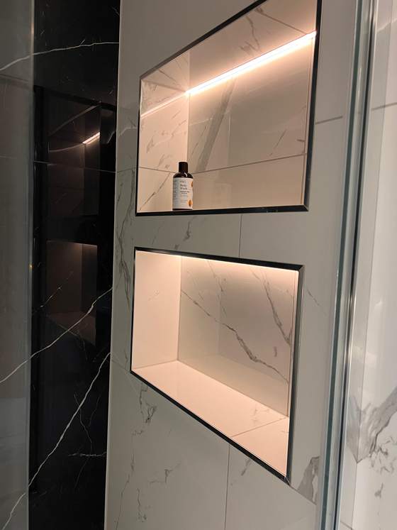 Lit shower niches in a marble-effect bathroom