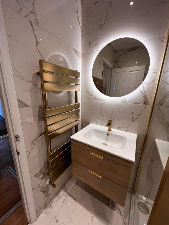 Marble bathroom with gold towel rail and round mirror