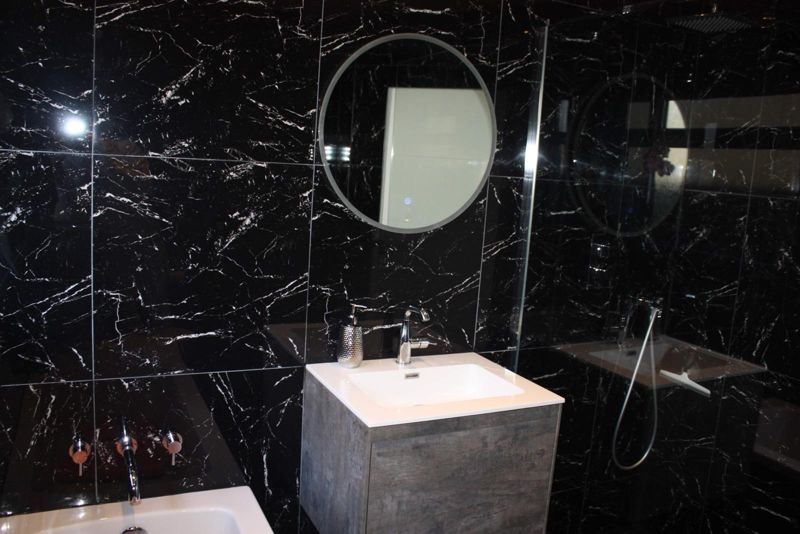 Black marble-effect bathroom with round mirror and concrete-look vanity