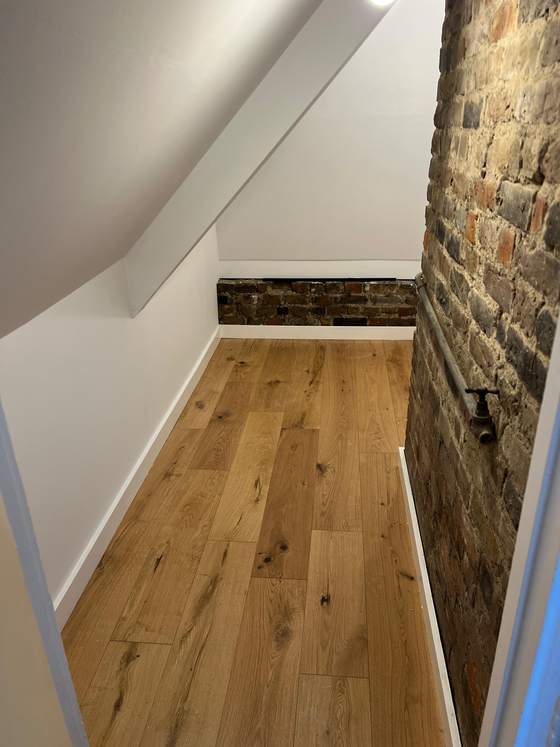 Oak flooring along a hallway with exposed brick