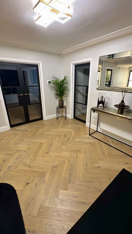 Oak herringbone flooring in a hallway with black glazed doors and console table