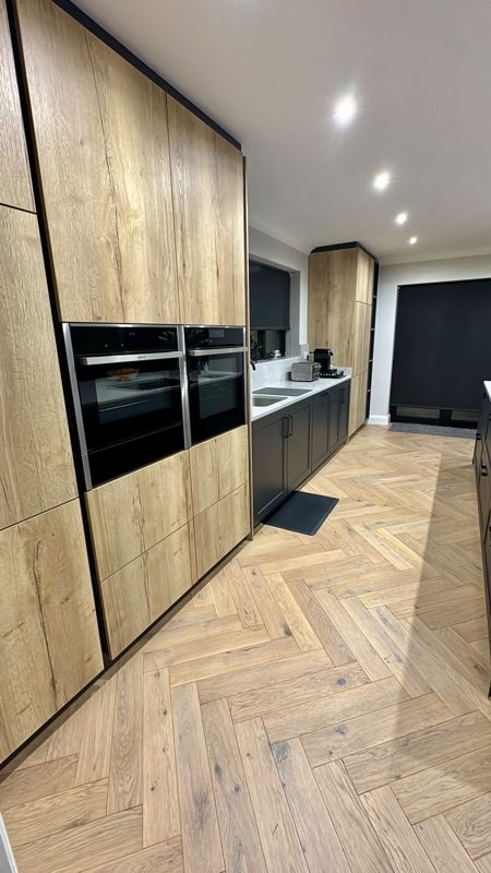 Oak herringbone flooring beside wood-effect tall kitchen units