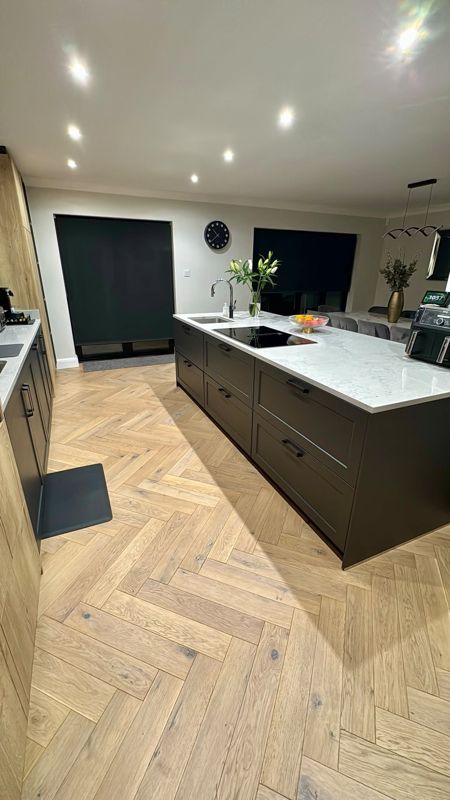 Oak herringbone flooring through a kitchen with dark island