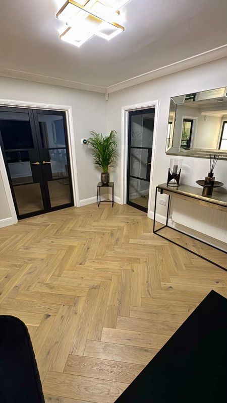 Light oak herringbone flooring in a hallway with black Crittall-style doors