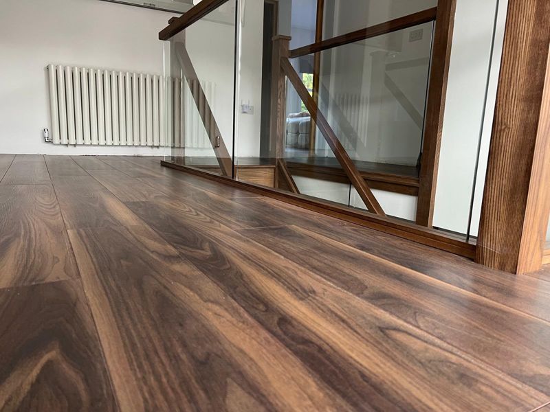 Dark walnut flooring on a landing with oak and glass balustrade