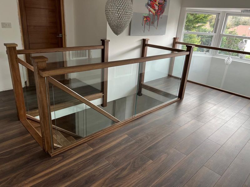Walnut flooring around an oak and glass staircase