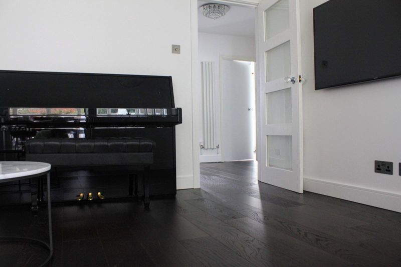 Lounge with black piano, wall-mounted TV and dark oak floor