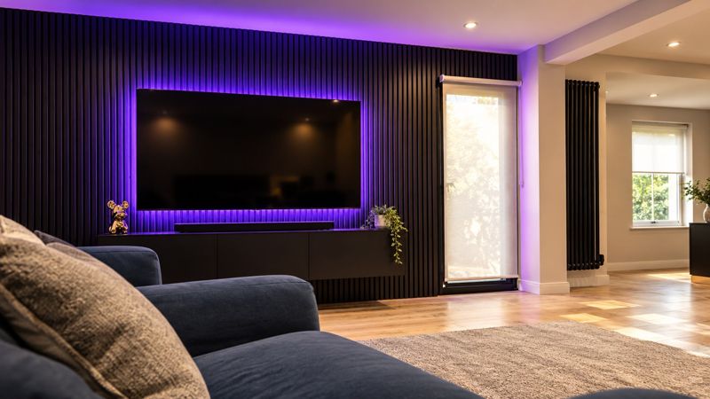 Black fluted media wall with purple LED backlighting and wall-mounted TV, by CVS Renovations