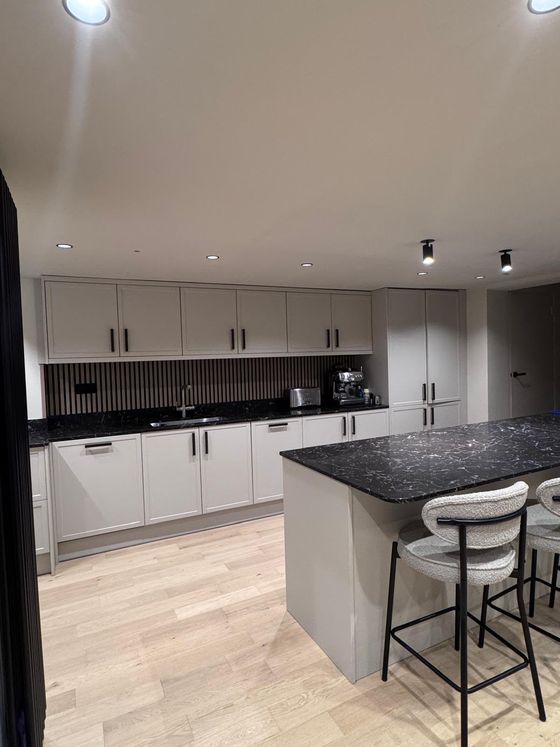 Open-plan grey kitchen with island seating and a slatted wood splashback